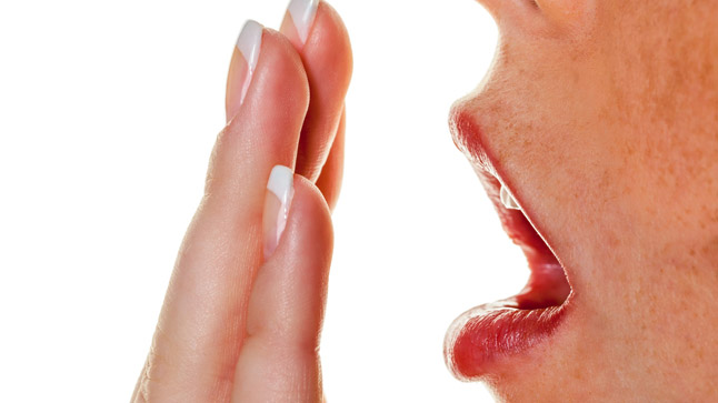 Mujer con halitosis se tapa la boca